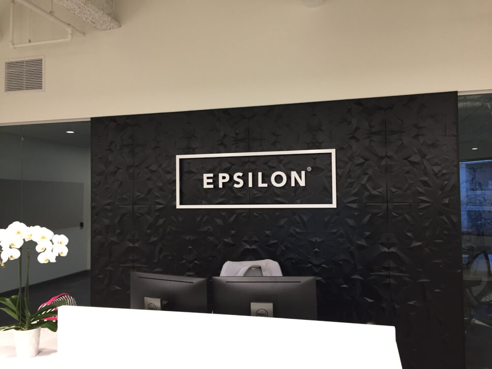 A visually-striking logo sign for Epsilon behind their reception desk