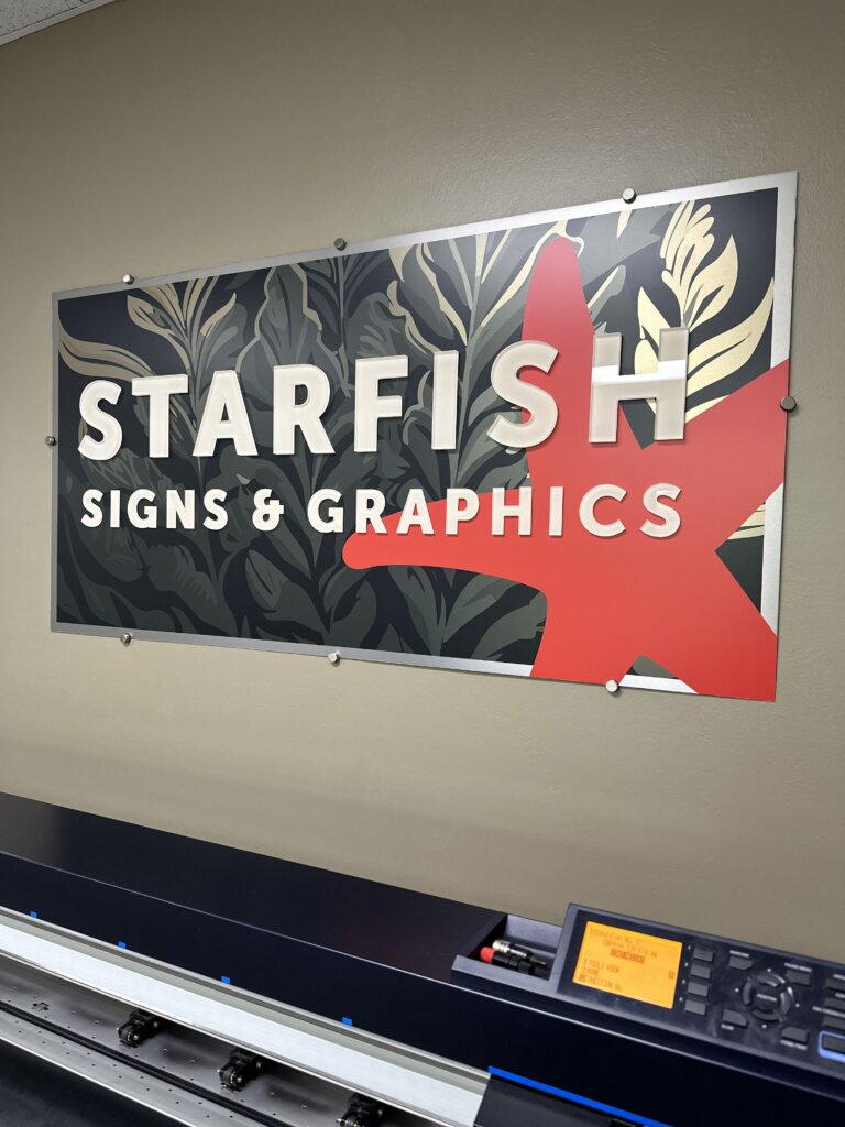 photograph of lobby sign - a mounted sign features the Starfish company name, with a red starfish on the right, all set atop a background of a kelp bed